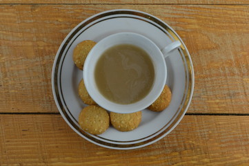 
cup of coffee and tasty cookies are on a wooden table