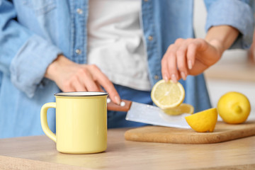 Beautiful young woman making tea with lemon at home, closeup
