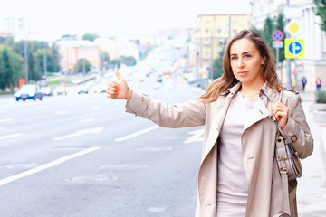 woman catches a car on the road, an adult young girl is waiting for a taxi, stops a passing vehicle, hitchhiking