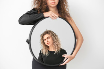 Beautiful model holding mirror with reflection of young woman on white background