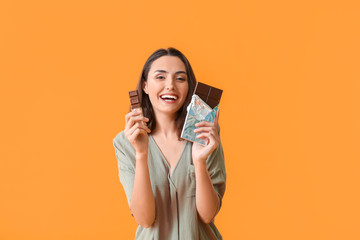 Beautiful young woman eating tasty chocolate on color background