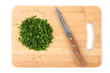 Cutting board and chopped herbs with a knife on white background