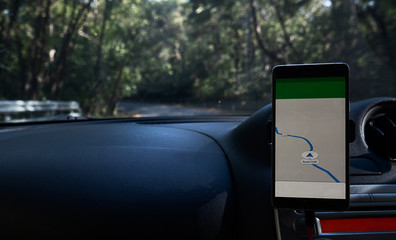 The map on the phone in the background of the dashboard and street in the forest A mobile phone with map GPS navigation
