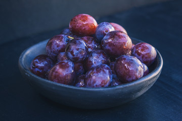 dark plate with fresh organic plums
