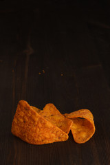 Mexican spicy tortilla chips on a dark background close up. Nachos with chilli pepper on dark wooden background with copy space.