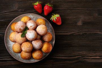 Rosy cheese balls with strawberry on a dark wooden background. Top view.