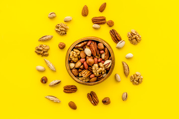 Fototapeta na wymiar Mixed nuts in bowl on yellow background top-down