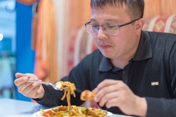 Man eating noodles in a cafe during lunch