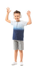 Cute little boy listening to music on white background