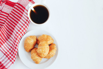 Mini croissants and cup of coffee on white background.