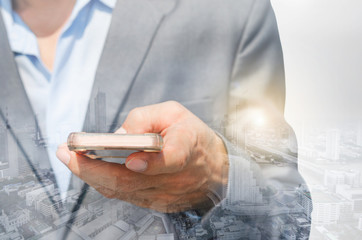 double exposure business man hands use smartphone typing on screen for working with technology wireless communication connection with cityscape building background.