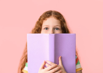 Cute little girl with book on color background