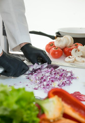 Chef cook cut red onion with a knife at the white table