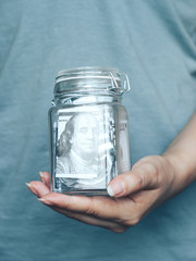 A woman is holding a jar of money in her hands