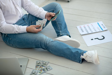Man sitting on the floor and counting the rest of money