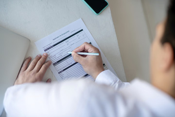 Dark-haired man in a white shirt signing the unemployment application
