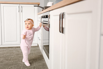 Fototapeta na wymiar Little baby near stove in kitchen. Child in danger