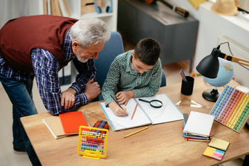 Grandfather and grandson working homework together. Grandpa and grandson enjoying at home.