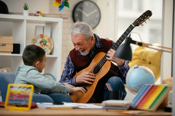 Grandpa and grandson playing guitar. Grandfather and grandson enjoying at home.	
