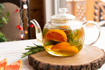 Glass teapot with fruit and herbs for healthy eating on a wooden table