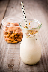 Almond milk in glass jar with straw on a wooden table, side view, milkshake
