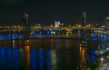 Obraz na płótnie Canvas main street bridge (John T. Alsop Jr.) in Jacksonville, Florida bathed in blue neon lights after dark. St. Johns river passes underneath.