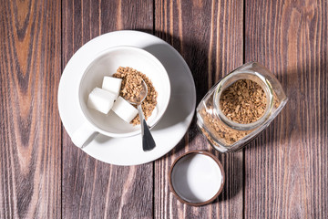freeze-dried coffee, a Cup filled with freeze-dried coffee and a piece of refined sugar at the bottom of the Cup, on a wooden table