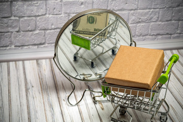 box in a shopping trolley. reflection in the mirror of a hundred dollars