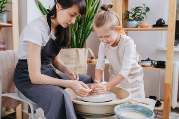 Potter watches boy as he enthusiastically tries to shape his first tableware