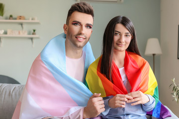 Portrait of young transgender couple with flags at home