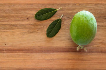 ripe feijoa fruit and leaves on wooden chopping board with copy space on left