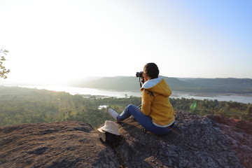 Woman sitting and taking pictures at the cliff in Pha Tam National Park, Ubon Ratchathani, Thailand.