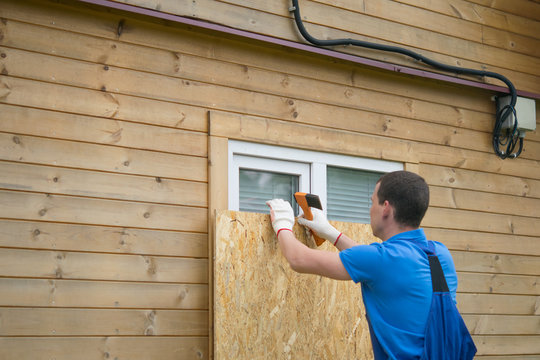 worker, boarded up the window of the house with a protective shield made of wood, from thieves, when moving to another address