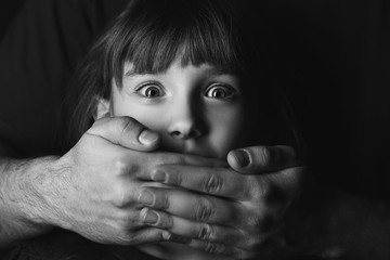 Father covering mouth of his scared little daughter, closeup. Concept of domestic violence