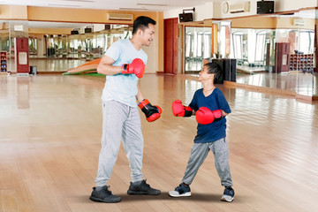 Young man and little son doing boxing exercise