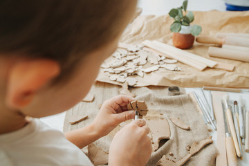 Little boy working with clay in a workshop, cutting it into leaf shape