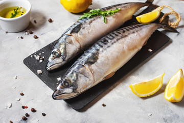 Fresh raw mackerel with lemon and spices on concrete background.