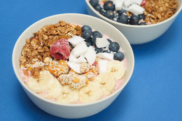 Handmade Bowl healthy tasty breakfast of yogurt, smoothie with granola, nuts, bananas and berries