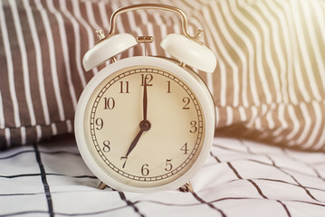 White vintage alarm clock and pillows in the bed. Wale up and morning concept