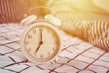 White vintage alarm clock and pillows in the bed. Wale up and morning concept