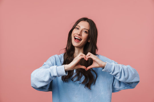 Image of young woman smiling and showing heart shape with fingers