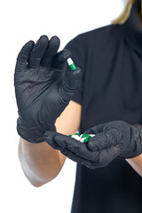 Close-up of the pills in the girl's hands, protected by black latex gloves, isolated on a white background. Vertical.