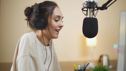 Young female streamer hosts a podcast and answers questions, working at a computer and talking to the audience, quarantine.