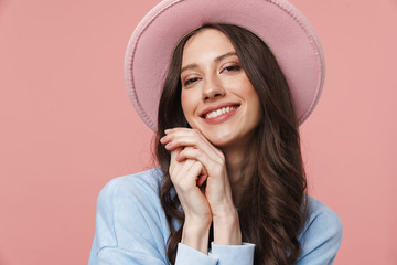 Image of young woman with long brown hair wearing hat smiling at camera