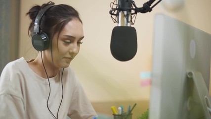 Young female streamer hosts a podcast and answers questions, working at a computer and talking to the audience, quarantine.