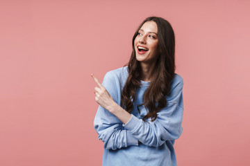 Image of young woman smiling and pointing finger at empty space