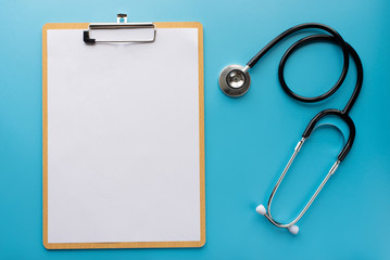 Stethoscope with clipboard on blue background
