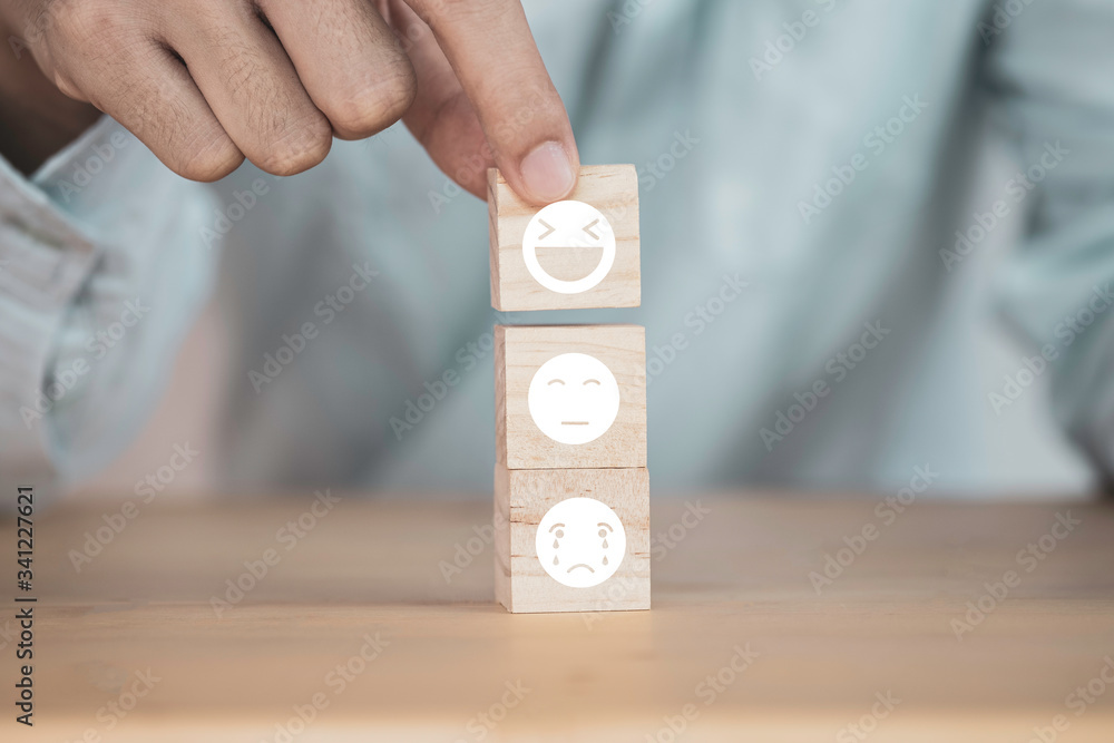 Poster customer hand putting happy and smile face emotion which print screen on wooden block on sad emotion