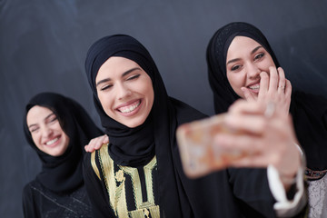 muslim women taking selfie picture in front of black chalkboard