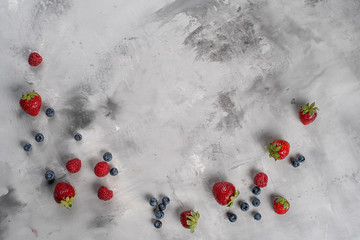 Frame of raspberries and blueberries. Flat lay composition. Gray concrete background. Top view. Copy space.